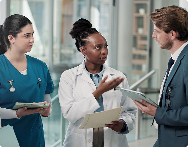 a doctor holding patient files having a conversation with two nurses